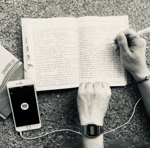 Person writing on notebook and listening to music